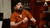 a man in an orange shirt is sitting in front of a sign that says annapurna studios