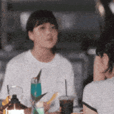 two women are sitting at a table with drinks and a lantern .
