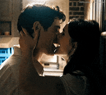 a man and woman are kissing in front of a brick wall