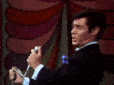 a man in a suit and tie is singing into a microphone in front of a colorful background