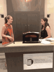 two women standing at a podium with a sign that says ' rowan music center for jewish student life ' on it