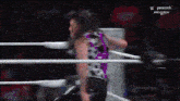 a woman in a purple shirt is in a wrestling ring with peacock on the screen