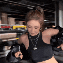 a woman wearing a black tank top and a necklace is standing in a warehouse .