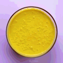 a person is pouring honey into a bowl of yellow sauce