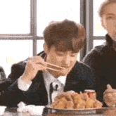 a man is eating fried chicken with chopsticks .