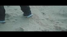 a person 's feet are shown walking on a sandy beach