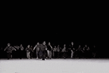 a group of people are dancing on a stage in a dark room .
