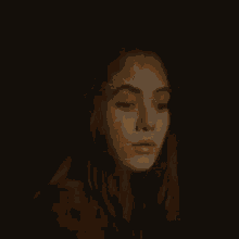 a close up of a woman 's face in the dark with a light shining on her face .