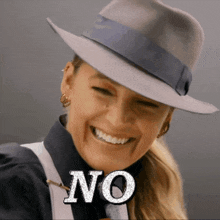 a woman wearing a fedora smiles with the word no on her face