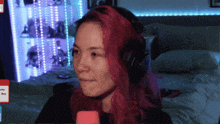 a woman with red hair is wearing headphones and holding a pink object