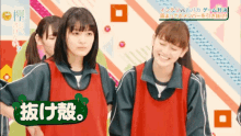 a group of girls are standing next to each other and one of them is wearing a red vest with chinese writing