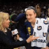 a woman is talking to a basketball player who is wearing a jersey that says gatorade on it .
