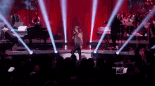 a woman singing into a microphone on a stage with a crowd watching