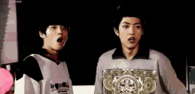 two young men are standing next to each other with their mouths open and one of them is wearing a le coq sportif shirt .