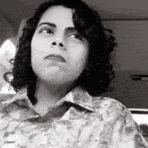 a woman with curly hair is wearing a floral shirt and making a face
