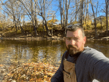 a man with a beard is standing next to a body of water