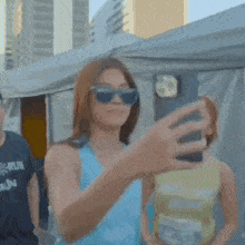 a woman wearing sunglasses is taking a picture of herself