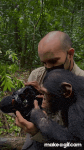 a man wearing a mask holds a canon camera while a chimpanzee looks on