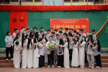 a group of students pose for a picture in front of a sign that says lễ tong kết năm học 2021 2025
