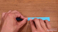 a person is holding a piece of blue paper on a wooden surface .