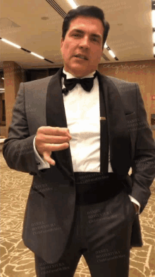 a man in a tuxedo stands in front of a wall that says daniel roaventura