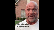 a bald man with a beard is standing in front of a brick house and making a funny face .