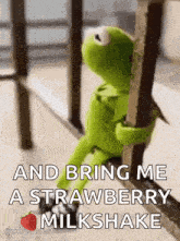 kermit the frog is sitting on a railing and holding onto a railing .