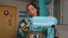 a woman in a plaid shirt is pouring something into a kitchenaid mixer