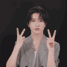 a man in a plaid jacket holds up his fingers with red lipstick on them