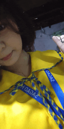 a woman wearing a yellow shirt with a blue lanyard that says ' aaaz ' on it