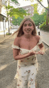a woman in a white floral dress is walking down the street