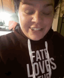 a woman is wearing a faith loves shirt and smiling