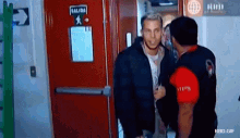 two men are standing in front of a red exit door with a sign that says salida on it