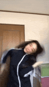 a woman in a blue jacket is dancing in a room .