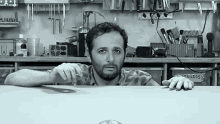 a black and white photo of a man peeking over a counter with a box that says sonudos on it
