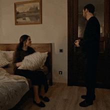 a man is carrying a blanket over a woman sitting on a bed