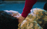 a woman in a floral dress is laying on the ground and someone is holding her neck