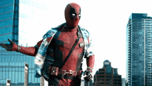 a man in a deadpool costume is standing in front of tall buildings