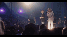 a man and a woman singing into microphones in front of a crowd of people