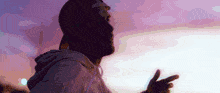 a silhouette of a man wearing a hat and a purple hoodie
