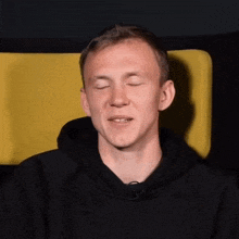 a man with his eyes closed and a black hoodie on