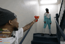 a man is holding a toy gun in front of a man in a white shirt and blue pants
