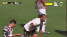 two soccer players are celebrating a goal with a free da zn logo in the background