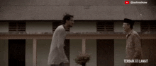 two men are hugging each other in front of a building with the words terbaik menjadi langit on the bottom