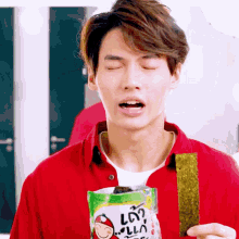 a man in a red shirt is holding a bag of seaweed that says ' la ' on it