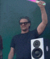a man wearing sunglasses is holding a rainbow colored light up stick over his head