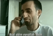 a man is talking on a cell phone with the words kral abim eyvallah abim written on the bottom