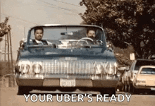 two men are driving a car down a street with the words `` your uber 's ready '' written on the side .