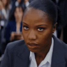 a woman in a suit and white shirt looks serious
