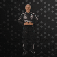 a man in a petronas suit stands in front of a dark background